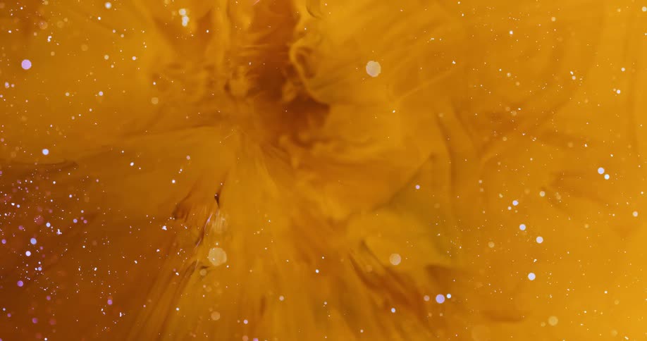 Dense yellow liquid in suction motion with small sparkling particles in an abstract manner