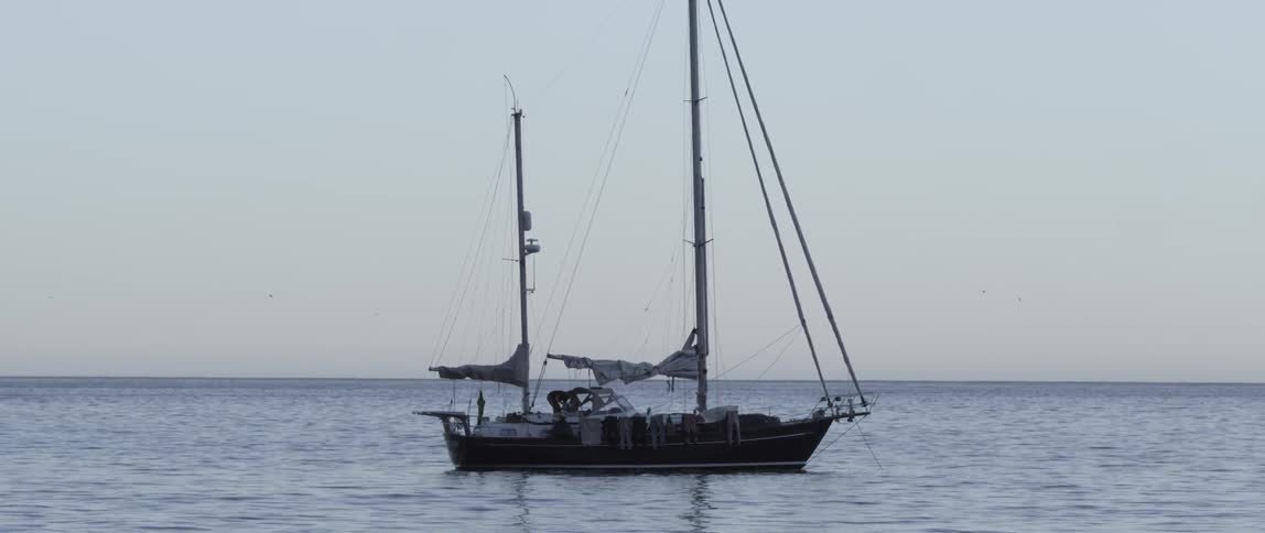 A boat is in the water with it's sails down