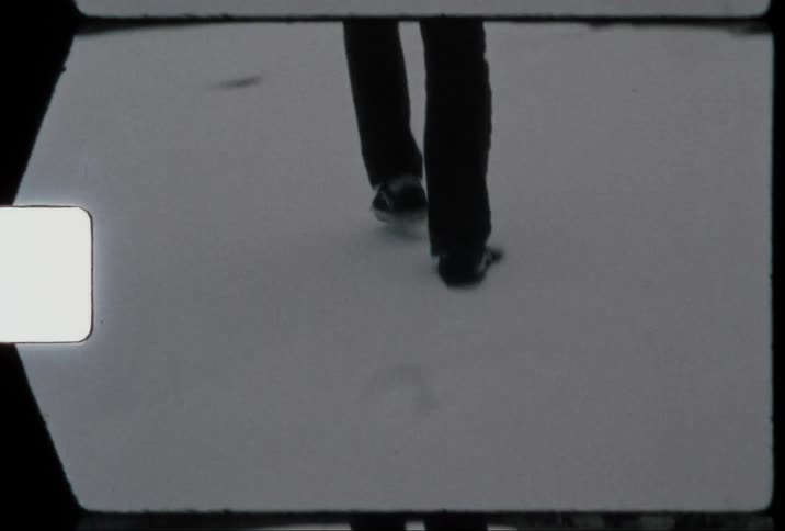 Man walking with his back facing the camera on snowcovered ground in the midst of the city