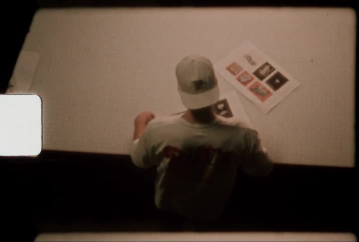 Person wearing cap sorts papers on table