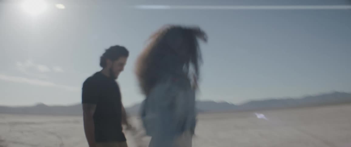 Three people are walking in a desert region with the camera moving rapidly