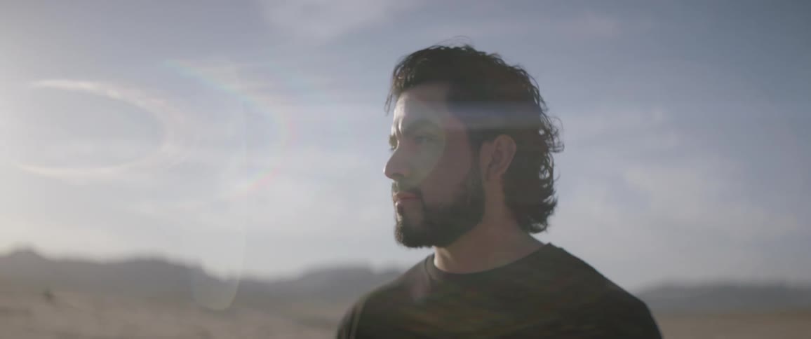Man stands outside in field on sunny day looking around