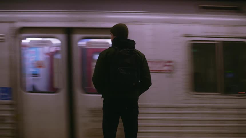 Man waits in terminal at night as subway passes