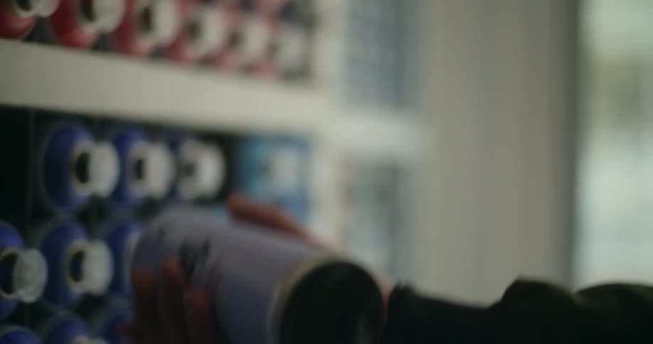 Person picking up a can of blue paint in a store