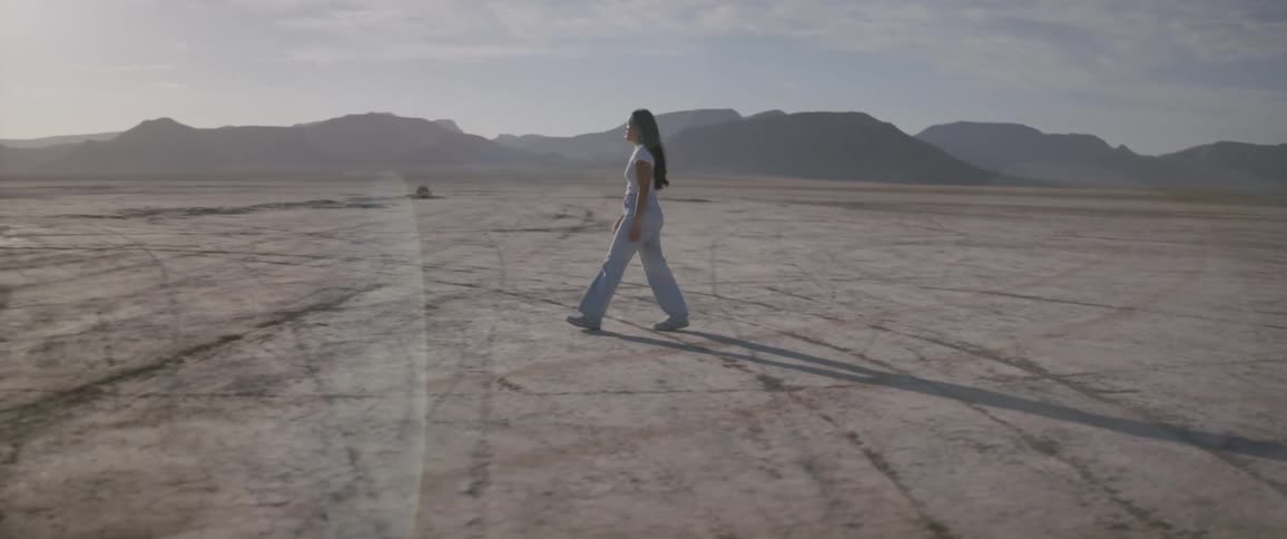 A woman walking alone in the same direction in a desert region