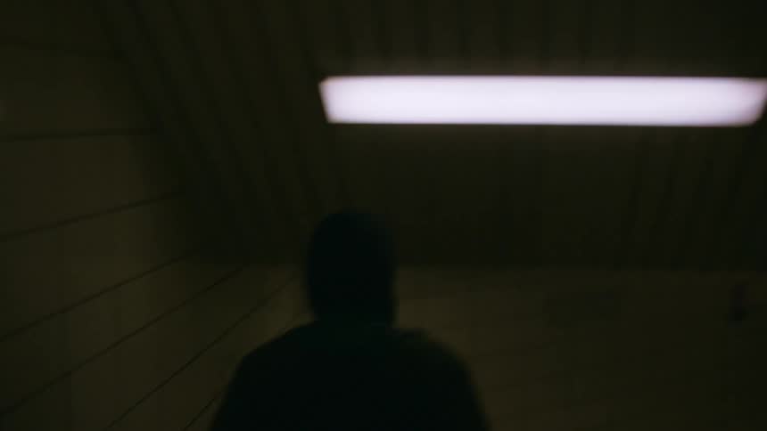 A man walking downstairs in a dimly lit hallway