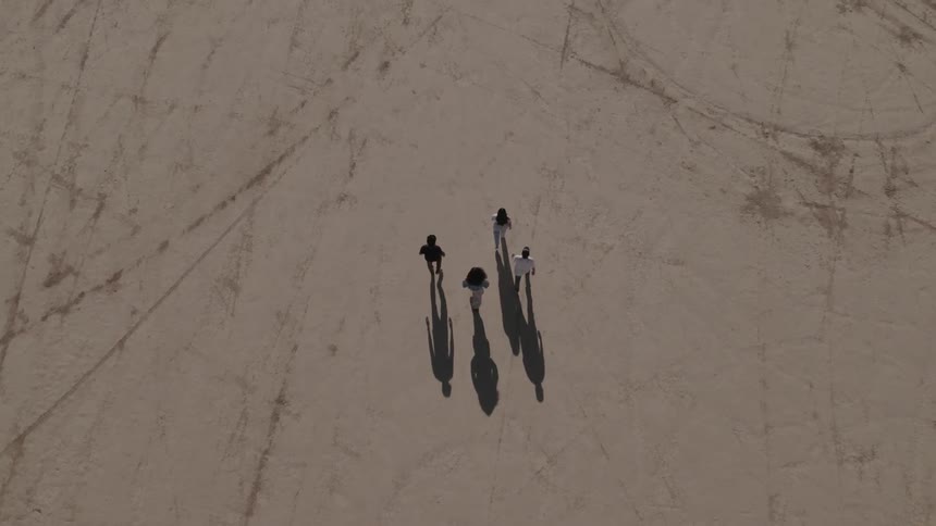 Four people walk forward across textured land