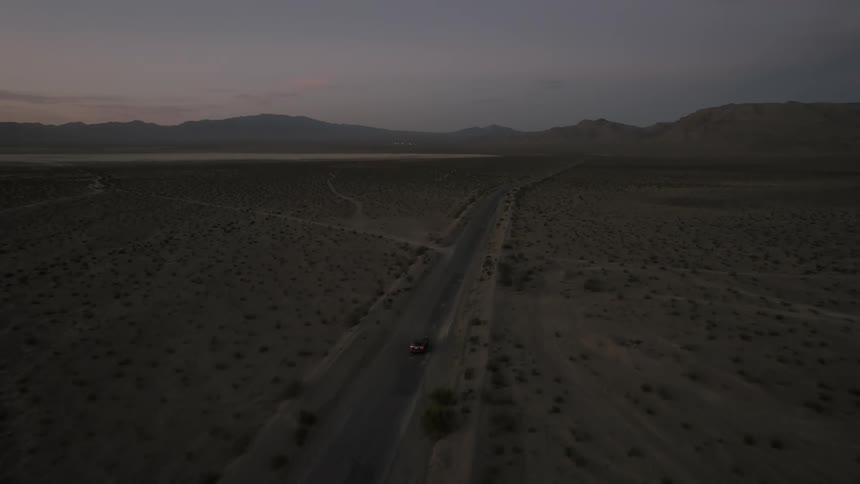 A car on a highway in the middle of the desert alone