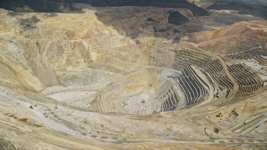  aerial footage showcasing the Bingham Canyon Mine (Kennecott Copper Mine) in Utah capturing the open pit mining in a sunny summer day with partly cloudy skies
