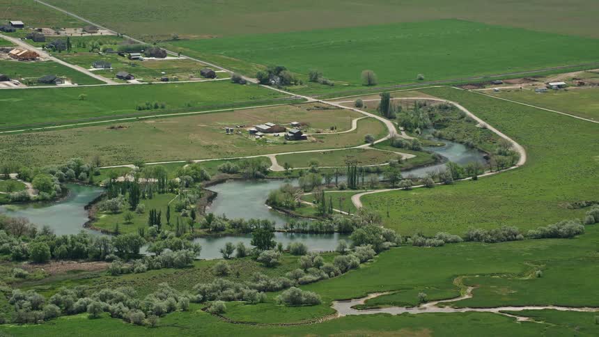  aerial footage showing a picturesque countryside with a barn Burraston Ponds and lush farmland in Mona Utah on a cloudy day