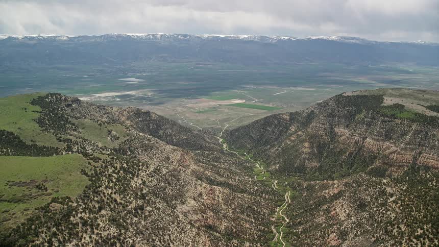 Aaerial view of an approaching valley over majestic mountain peaks in the Wasatch Range Utah on a cloudy day