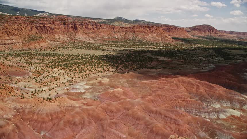 Approaching a mesa overlooking valley desert vegetation in Capitol Reef National Park Utah on a partly cloudy day during summer