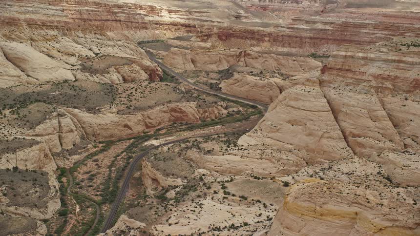 Aerial view of a desert road passing through Waterpocket Fold rock formations in Capitol Reef National Park Utah on a partly cloudy day