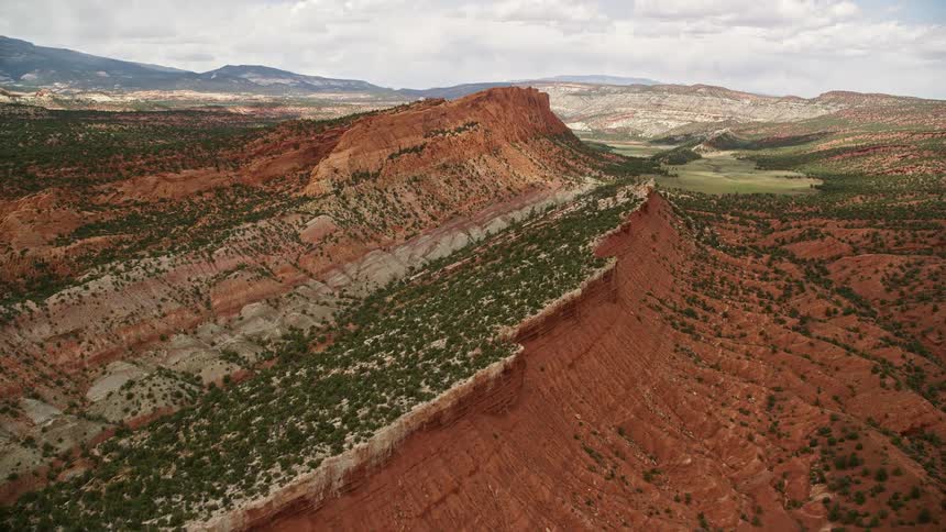  aerial footage panning across the top of a mesa in Capitol Reef National Park Utah showcasing the arid desert landscape and famous table mountains