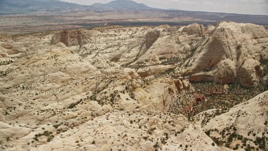 Aerial footage flying over Waterpocket Fold rock formations and canyons in Capitol Reef National Park Utah on a cloudy day