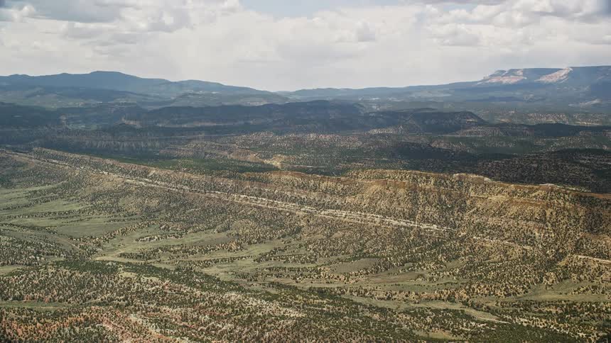 Approaching a lush green mountain ridge from a wide valley in Grand Staircase-Escalante National Monument Utah during a partly cloudy day in summer