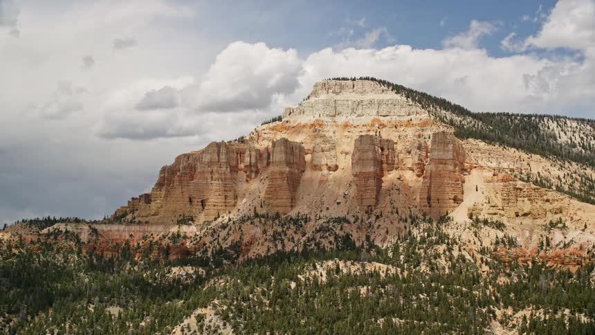 Aerial view of Barney Top Mesa in Utah featuring majestic mountains arid desert landscape and partly cloudy skies