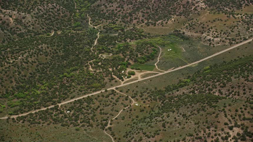 Aerial footage of a country road passing through tree-covered hillsides in Richfield Utah during summer