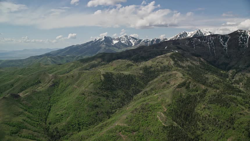 Approaching green ridges and snowy peaks of Oquirrh Mountains in Utah during summer captured in stunningaerial footage