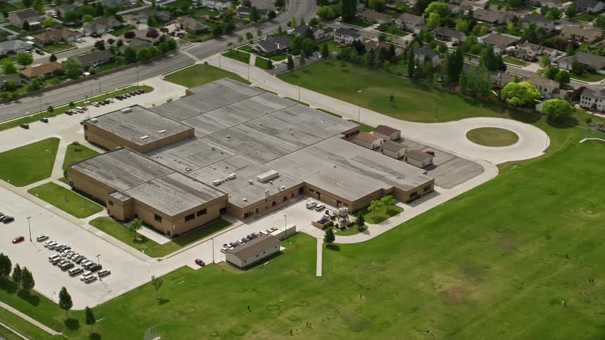 Aerial footage of West Hills Middle School and grass fields in West Jordan Utah shot during a partly cloudy day in summer