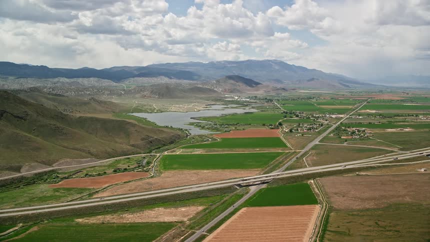 Aerial view of a rural area with roads passing through small towns farmland and a lake surrounded by mountains in Sigurd Utah during a sunny day in summer
