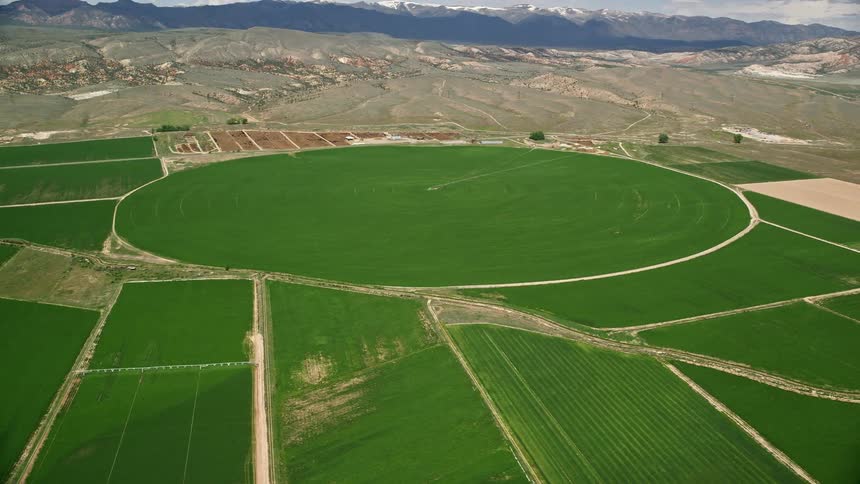 Aerial view of a large circular crop field surrounded by farmland in Aurora Utah during a sunny day with partly cloudy skies
