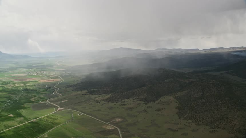  aerial footage of rain falling on mountains trees and a farming community in Fishlake National Forest Utah showcasing the rustic and agricultural landscape during a rainy day in the Southwest United States