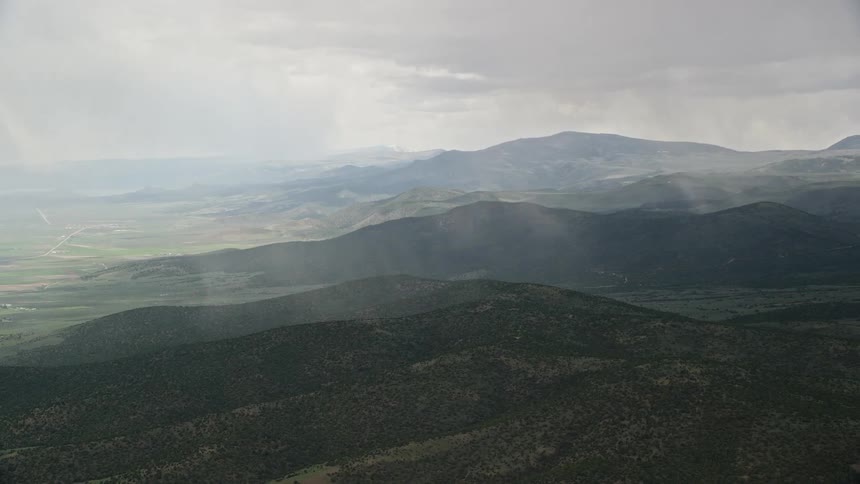  aerial footage of rain falling on tree covered hillsides with fog settling over the land in Fishlake National Forest Utah