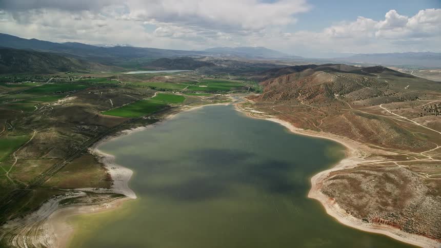 Aerial footage of low water levels in Gunnison Reservoir surrounded by a valley captured in Utah during summer