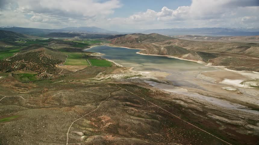 Approaching the low water Gunnison Reservoir in Sanpete County Utah with partly cloudy skies - aerial footage