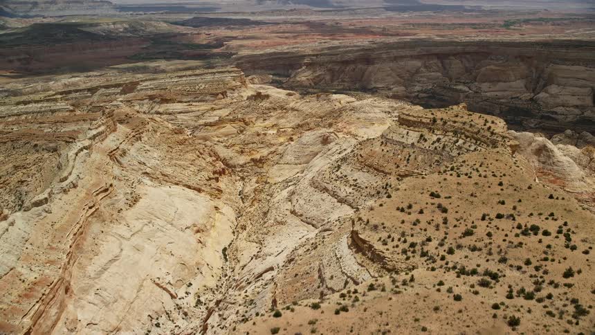 Approaching box canyon from over mesa in Capitol Reef National Park Utah showcasing the arid desert landscape and famous striations shot from an aerial POV