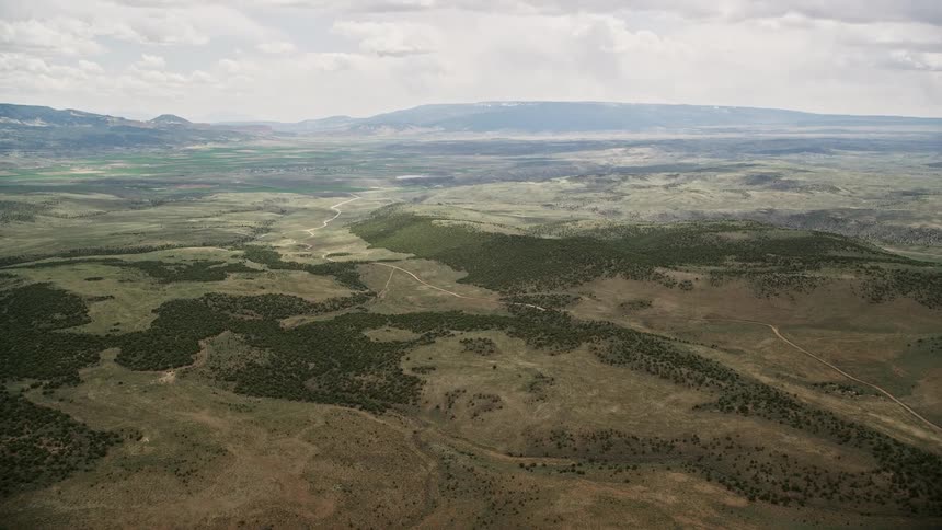 Aerial view of green hills trees and a country road in Fishlake National Forest Utah on a cloudy day