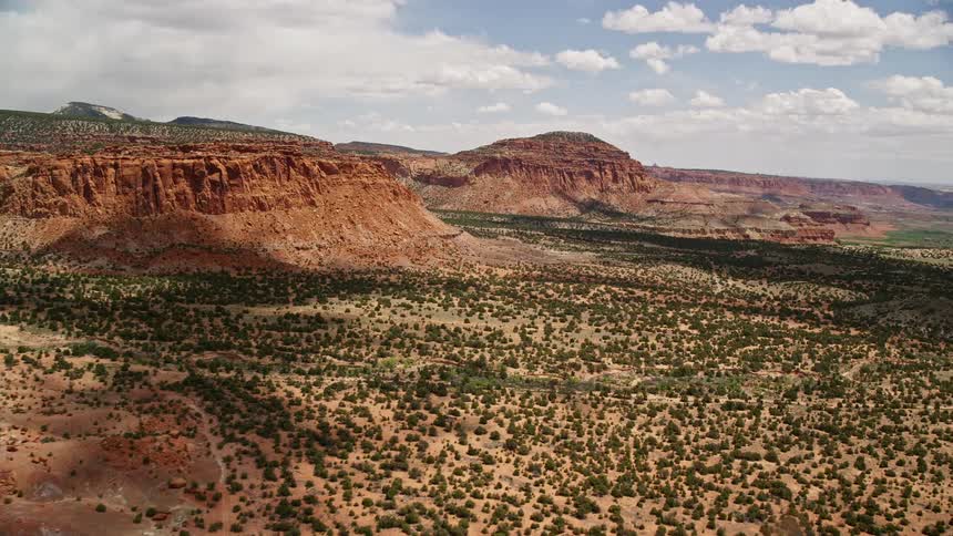 an aerial view of mesas and a butte in Capitol Reef National Park Utah with stunning desert landscapes and partly cloudy skies