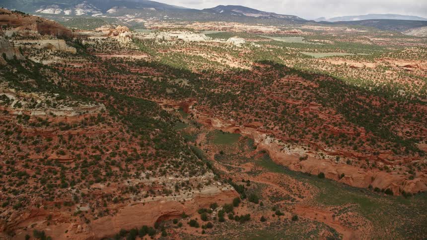 Approaching canyons and mountains reveal a green valley in Capitol Reef National Park Utah during a partially cloudy day
