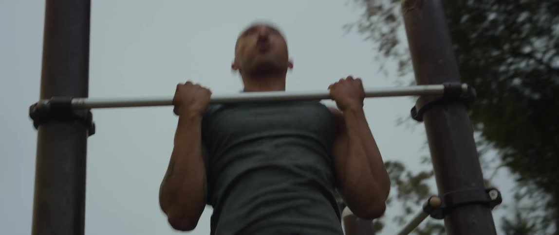 Man does chin ups outdoors
