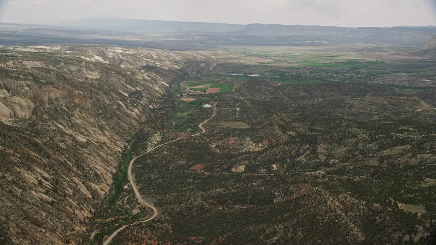 an aerial pan over Hells Backbone Road showcasing the stunning mountainous landscape of Grand Staircase-Escalante National Monument in Utah during a partly cloudy day