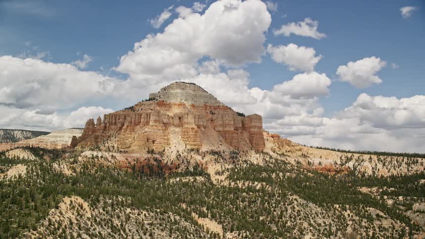  aerial stock footage capturing the breathtaking view of Barney Top Mesa rising above the desert vegetation and trees amidst a partly cloudy day in Utah's wilderness during summer
