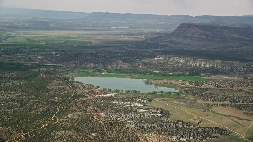 Aerial footage of a reservoir in the Grand Staircase-Escalante National Monument Utah surrounded by small grasses during a partly cloudy day