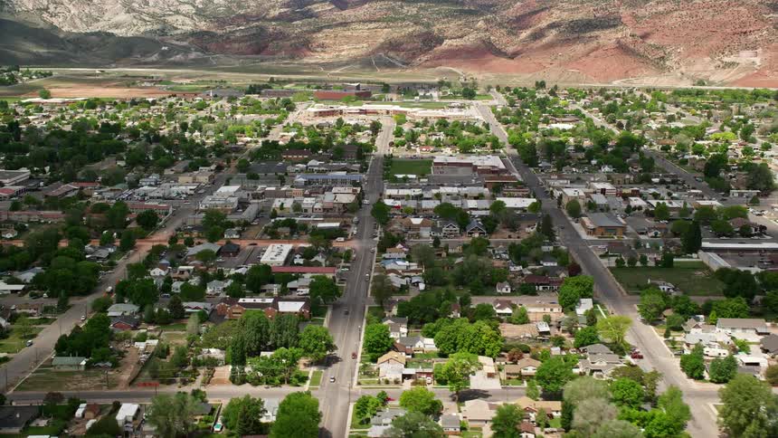 Aerial footage of small town neighborhoods and shops in Richfield Utah during the summer with a rustic and rural residential setting shown from a side view perspective
