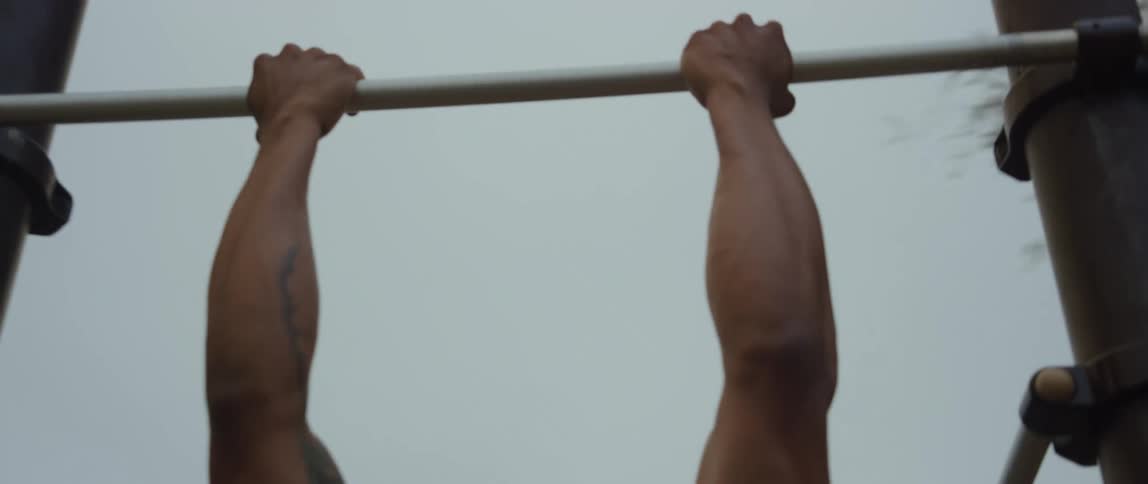 A man hypes himself up before doing pull ups at an outdoor gym