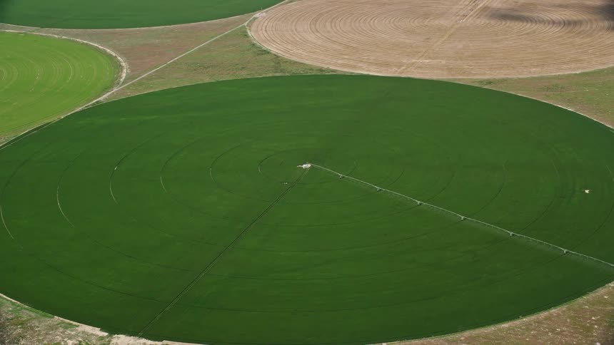 Approaching aerial view of a large circular crop field in Elberta Utah with a tilt down to showcase the center pivot irrigation system
