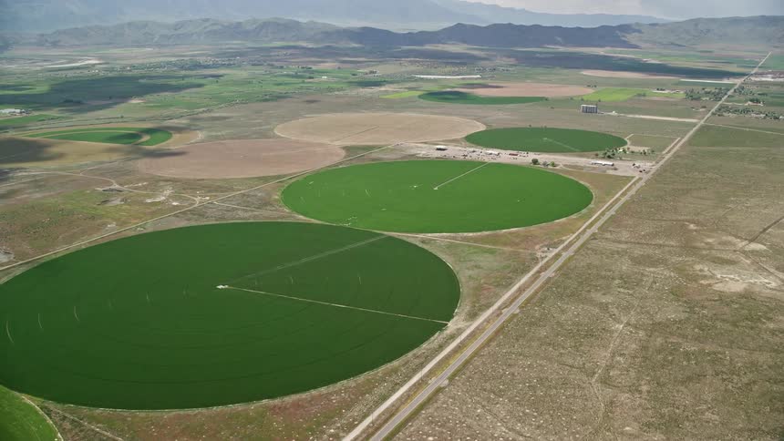  aerial footage of flying over vast circular crop fields in Elberta Utah showcasing the rustic and agricultural landscapes of the Southwest United States during a sunny summer day
