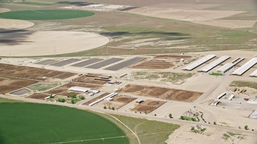 Aerial footage of circular crop fields greenhouses and ponds in Elberta Utah during the summer