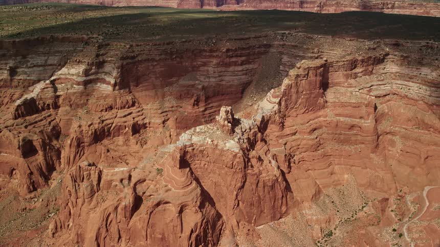 Approaching butte in an arid canyon tilting to a bird's eye view of Navajo Nation Reservation in Utah showcasing the natural beauty of the Southwest United States during daytime in summer