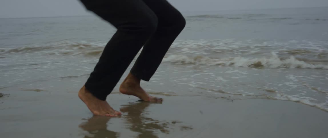 Man performing burpee exercise on the sand by the beach and the sea
