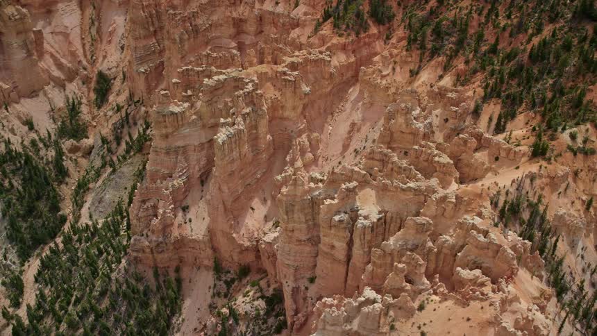  aerial footage of orbiting hoodoos amidst pink cliffs in Bryce Canyon National Park Utah showcasing the famous rock formations and striations on a partly cloudy day