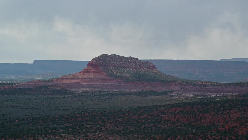 Aerial footage of passing by Steamboat Rock butte partially obscured by fog in Glen Canyon National Recreation Area on an overcast day in Utah during summer
