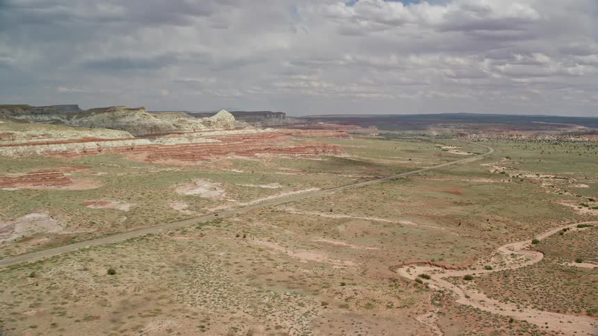 Aerial footage of a descent and approach towards Highway 89 showcasing the stunning Plateau and canyons of Glen Canyon National Recreation Area on a partly cloudy day in Utah and Arizona