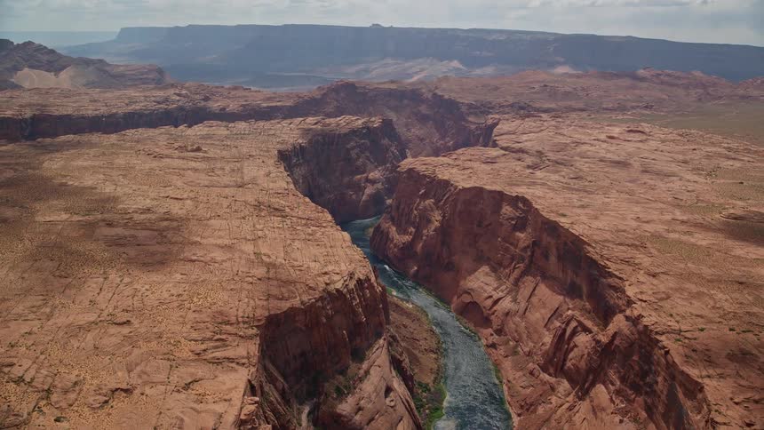 Aerial footage of the Colorado River flowing through Glen Canyon Arizona surrounded by desert canyons during a sunny day in Utah