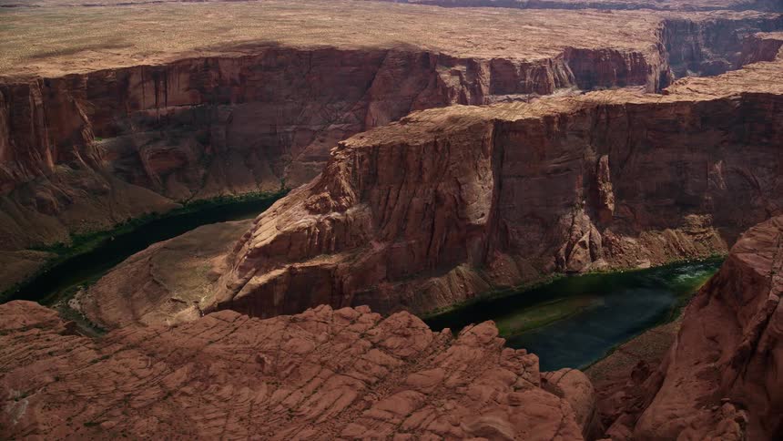  aerial footage captures the breathtaking beauty of Horseshoe Bend and the Colorado River flowing through the deep Glen Canyon in Arizona during a sunny day in summer